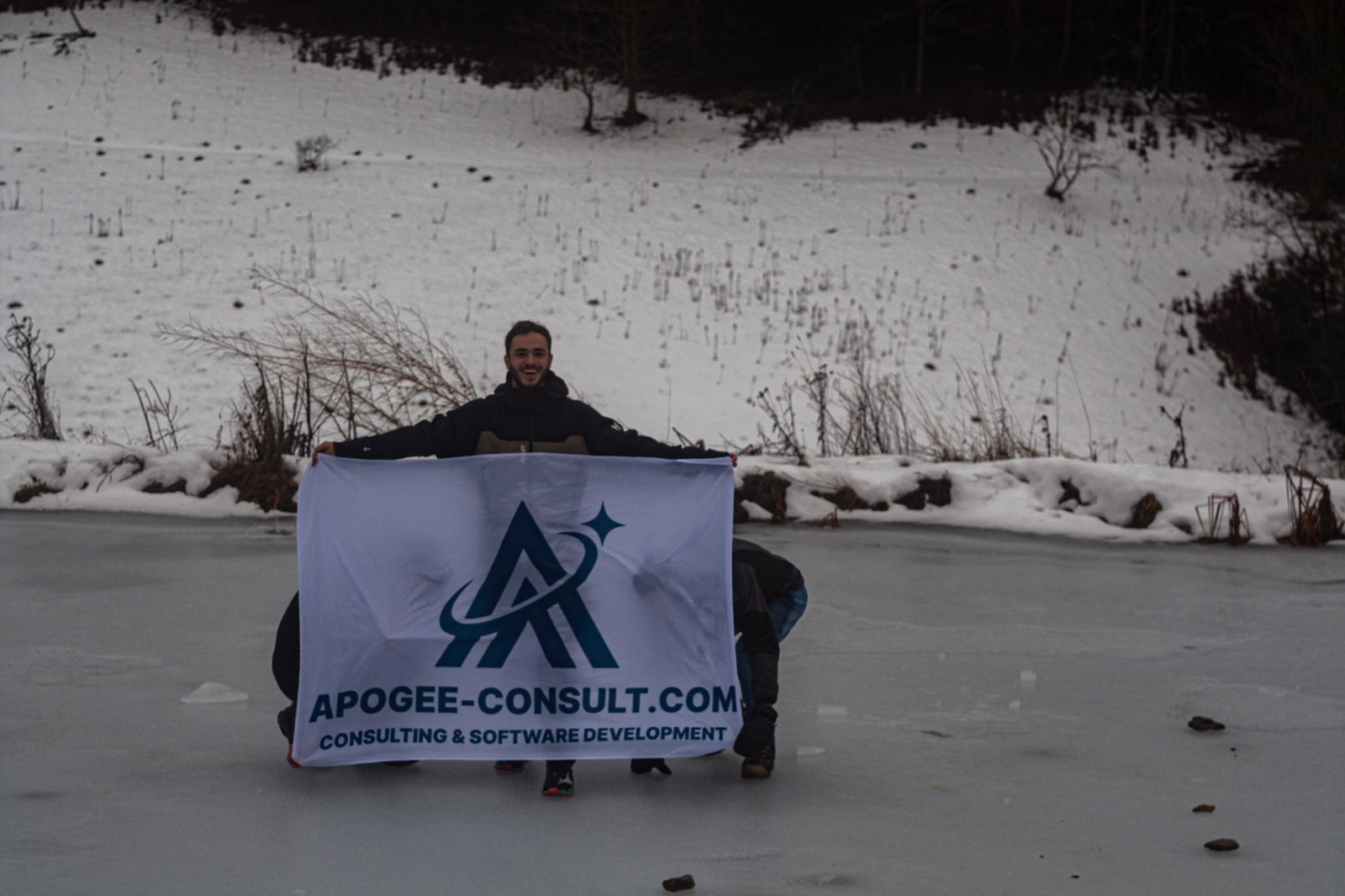 Mathieu Ponton, CTO chez Apogée Consult, tenant la bannière Apogée Consult en extérieur (consulting et développement logiciel)